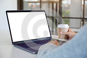 A woman using and touching on laptop touchpad with blank white desktop screen while drinking coffee