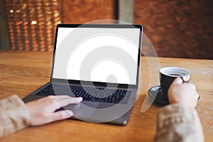 A woman using and touching on laptop touchpad with blank white desktop screen while drinking coffee