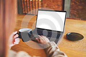 A woman using and touching on laptop touchpad with blank white desktop screen while drinking coffee