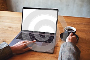 A woman using and touching on laptop touchpad with blank white desktop screen while drinking coffee