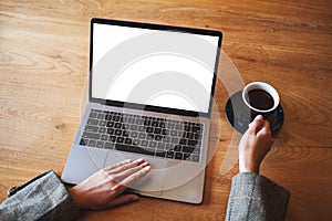 A woman using and touching on laptop touchpad with blank white desktop screen while drinking coffee