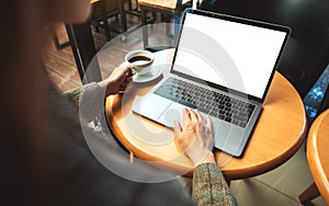 A woman using and touching on laptop touchpad with blank white desktop screen while drinking coffee