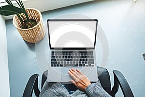 A woman using and touching on laptop touchpad with blank white desktop screen in office