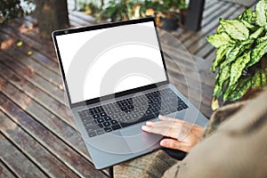 A woman using and touching on laptop touchpad with blank white desktop screen in the outdoors