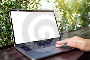 A woman using and touching on laptop touchpad with blank white desktop screen in the outdoors