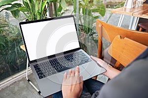 A woman using and touching laptop touchpad with blank white desktop screen while sitting in cafe