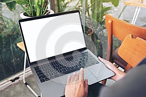 A woman using and touching laptop touchpad with blank white desktop screen while sitting in cafe