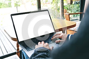 A woman using and typing on laptop keyboard with blank white desktop screen