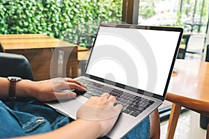 A woman using and typing on laptop keyboard with blank white desktop screen