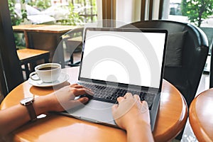 A woman using and typing on laptop keyboard with blank white desktop screen