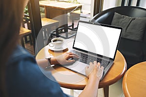 A woman using and typing on laptop keyboard with blank white desktop screen