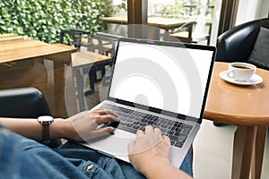 A woman using and typing on laptop keyboard with blank white desktop screen