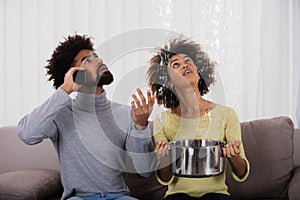 Woman Using Utensil For Collecting Water Leaking From Ceiling