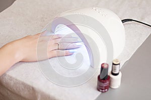 Woman using UV light dryer. Manicure, spa salon concept. Beauty and fashion
