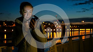 Woman using vertical smartphone on deck of cruise ship at night