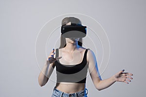 Woman using virtual reality glasses in a studio. Business woman wearing VR goggles and interacts with cyberspace using