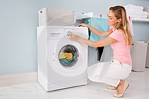 Woman Using Washing Machine In Utility Room