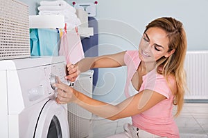 Woman Using Washing Machine In Utility Room