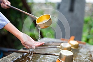 Woman using the water bamboo ladle for purification