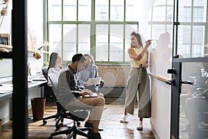 Woman using whiteboard in a small team meeting photo
