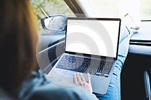 A woman using and working on laptop computer with blank desktop screen in the car