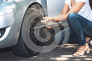 Woman using a wrench, which is a device for changing tires a car On the road alone
