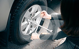 Woman using a wrench, which is a device for changing tires Pickup truck