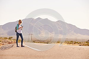 Woman On Vacation Hitchhiking Along Road Using Mobile Phone