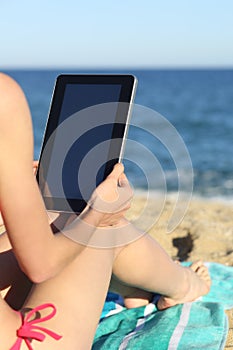 Woman on vacations reading a tablet on the beach