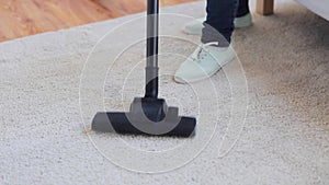 Woman with vacuum cleaner cleaning carpet at home