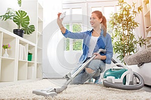 Woman with vacuum cleaner cleaning carpet and taking selfie