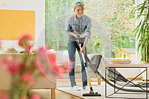 Woman is vacuuming beige carpet