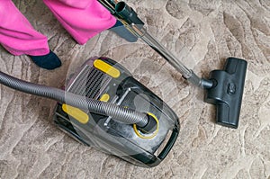Woman is vacuuming carpet with vacuum cleaner