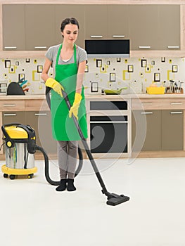 Woman vacuuming kitchen floor