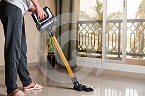 Woman vacuuming the living room with cordless vacuum cleaner