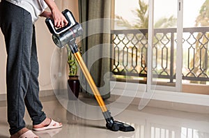 Woman vacuuming the living room with cordless vacuum cleaner photo