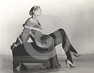 Woman in velvet dress sitting on footstool