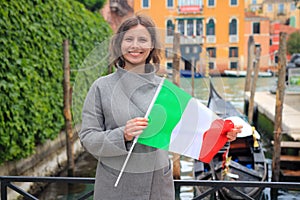 Woman in Venice with italian flag in hands. Girl on gondola in canal background. Happy tourist in Venezia, Italy