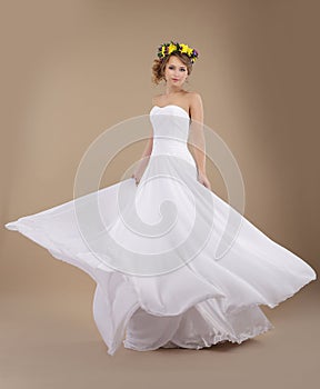 Woman in Vernal Wreath of Flowers in Flying Wedding Dress