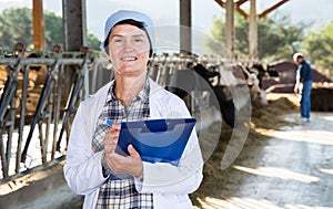 Woman veterinarian with clipboard on cow farm