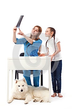 Woman veterinarian doctor showing a x-ray of a dog to little girl. Medicine and health care concept.