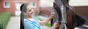 Woman veterinarian holding reins of horse at farm