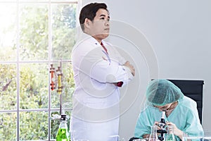 Woman veterinary student looking through a microscope near test tube