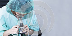 Woman veterinary student looking through a microscope near test tube