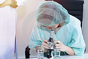 Woman veterinary student looking through a microscope near test tube