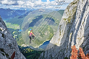 Woman on via ferrata ladder above Gosau lake, on the Intersport Klettersteig Donnerkogel route, in Austria. photo