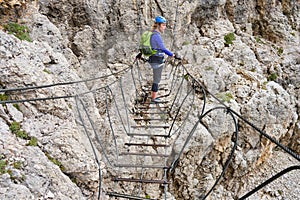 Woman on a via ferrata suspended wire bridge at Cesare Piazzetta klettersteig route, Sella group, Dolomites mountains, Italy