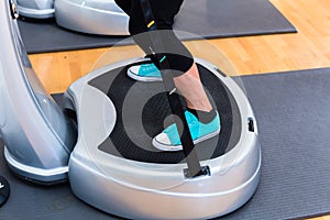 Woman on vibrating plates in gym training photo