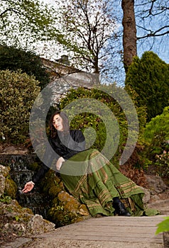 Woman in Victorian dress with hand in waterfall in park