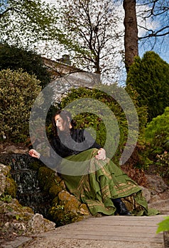 Woman in Victorian dress playing with water of waterfall